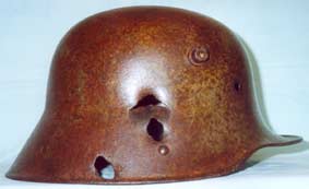 Modèle militaire allemand 1916 vert, légèrement repeint brun camouflage de tranchées automne/hiver. Il a été frappé latéralement du haut vers le bas par un groupement de 3 billes d'obus à shrapnells en son point de construction le plus faible. Le soldat touché entre la tempe droite et les cervicales a forcément été tué sur le coup.