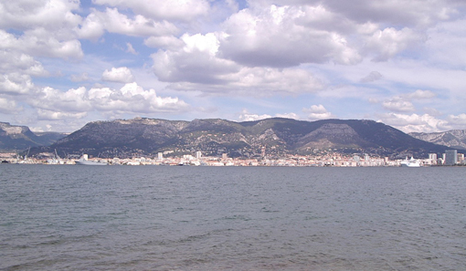Au creux de la rade, la ville et le port au pied du mont Faron. Le fort se situe &agrave; mi-penteouest du massif (&agrave; gauche sur la photo)